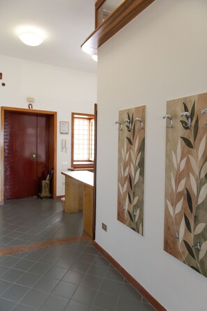A hallway with a wooden door, a window, and a wall-mounted artwork. - Toledo Skyview: Panoramic Penthouse in the Heart of Naples (Napoli)