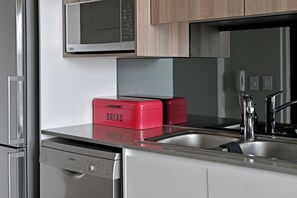 A kitchen with a Bosch dishwasher, a red bread box, a microwave, and a sink with a faucet. - Sleek Studio with City Skyline Views in Cape Town perfect for your getaway (Cape Town)