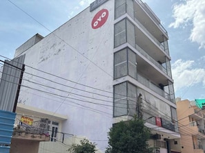 A multi-story building with a prominent red logo on the side. - Collection O Sadar Bazar Gurgaon (Gurugram)