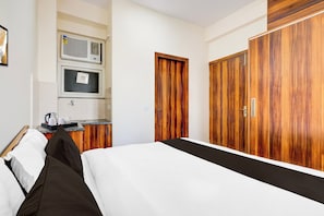 A hotel room with a bed, a desk with a kettle, a television, and wooden wardrobes. - Collection O Sadar Bazar Gurgaon (Gurugram)