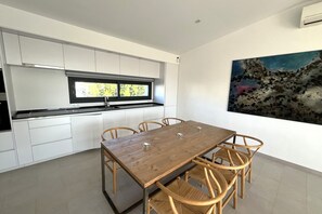 Eine moderne Küche mit weißen Schränken, einem Holztisch und einem großen Fenster.