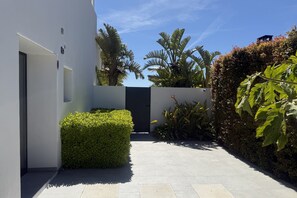 A modern building with a clean, geometric design, featuring a narrow pathway, neatly trimmed hedges, and a variety of tropical plants. - Villa 'Casa Celestella' near the beach with private pool, sea & mountain views (Benissa)