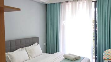 Een slaapkamer met een bed, een raam met gordijnen en uitzicht op buiten.