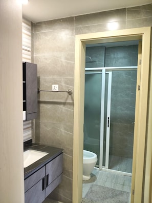 Een badkamer met een douchecabine, toilet en een wastafelmeubel met een wastafel.