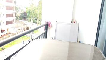 Een balkon met een tafel en stoelen, een whiteboard en uitzicht op gebouwen en groen.