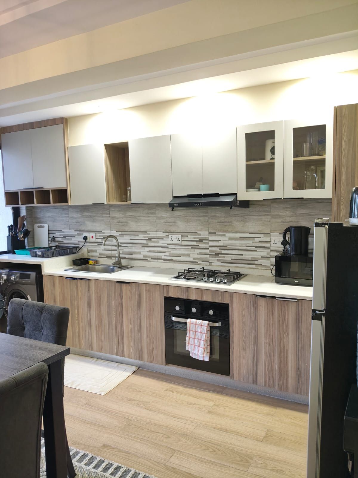 A modern kitchen with a central island, built-in appliances, and a dining area with a table and chairs.