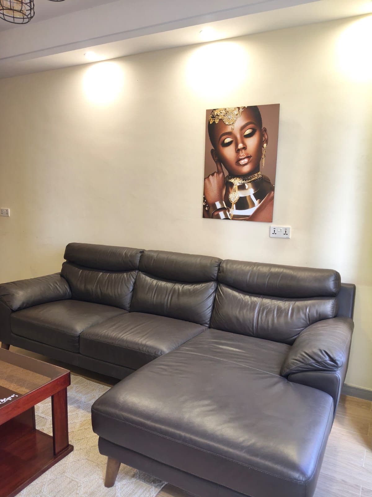 A sectional sofa in a living room with a painting on the wall.