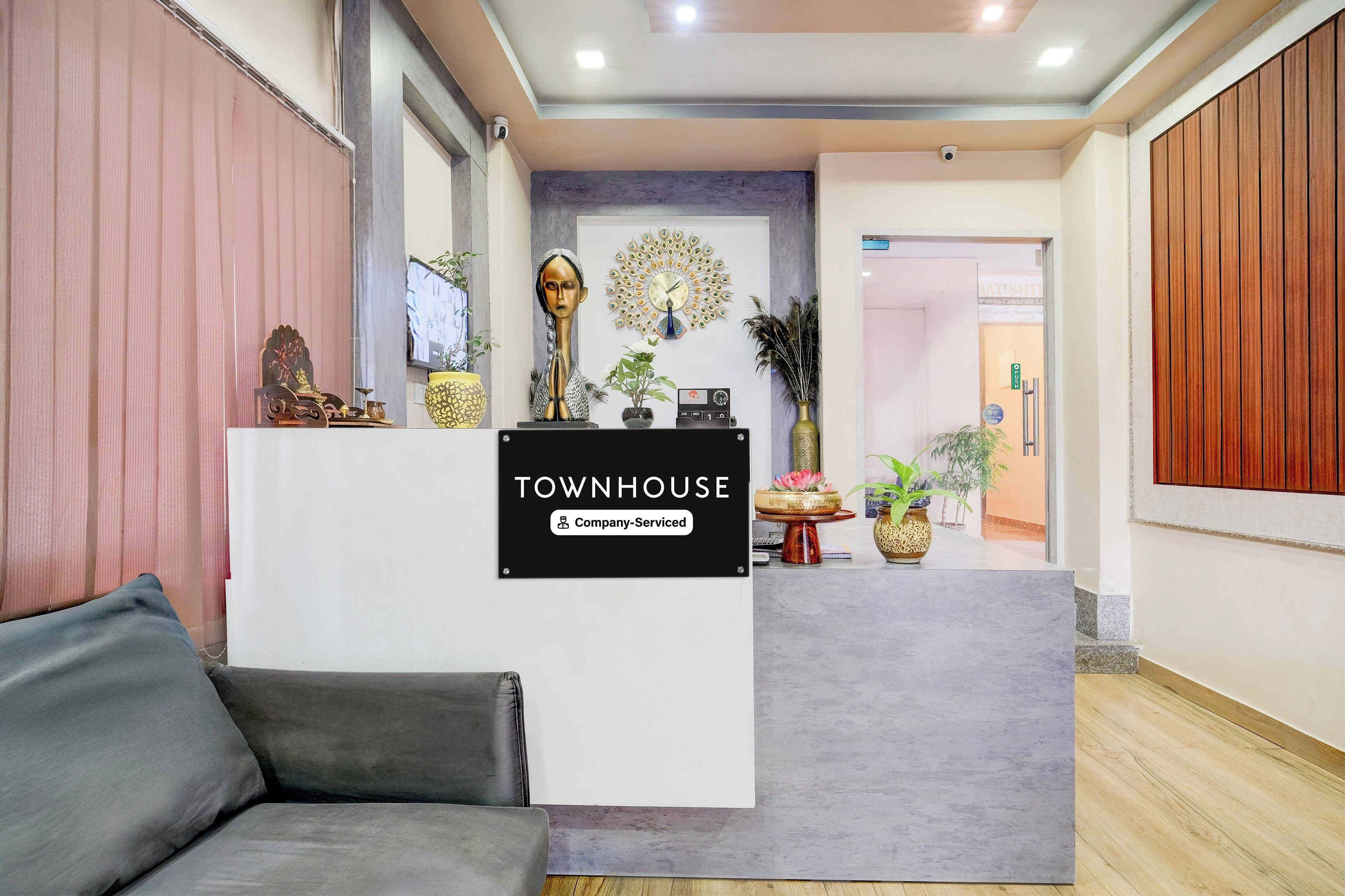 A reception area with a 'Townhouse' sign, a sofa, decorative items, and a peacock wall art.