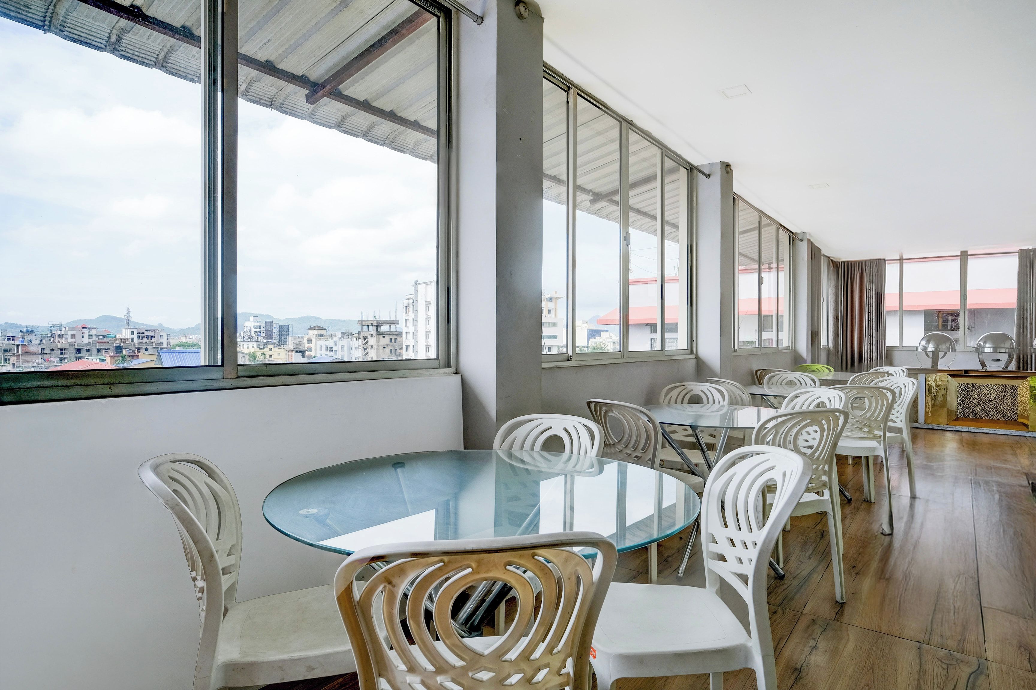 A spacious room with large windows, a glass table, and white chairs.