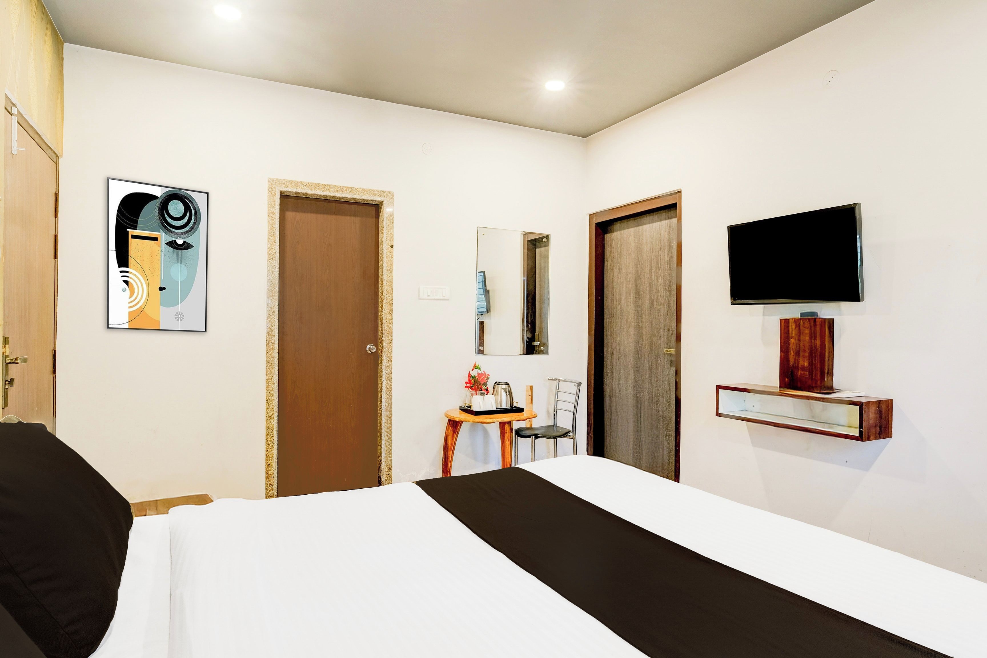 A hotel room with a bed, a television mounted on the wall, and a small table with a chair.