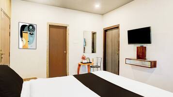 A hotel room with a bed, a television mounted on the wall, and a small table with a chair.