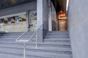 A staircase with metal handrails leading to a reception area with a sign for 'The Classic Crown' hotel.
