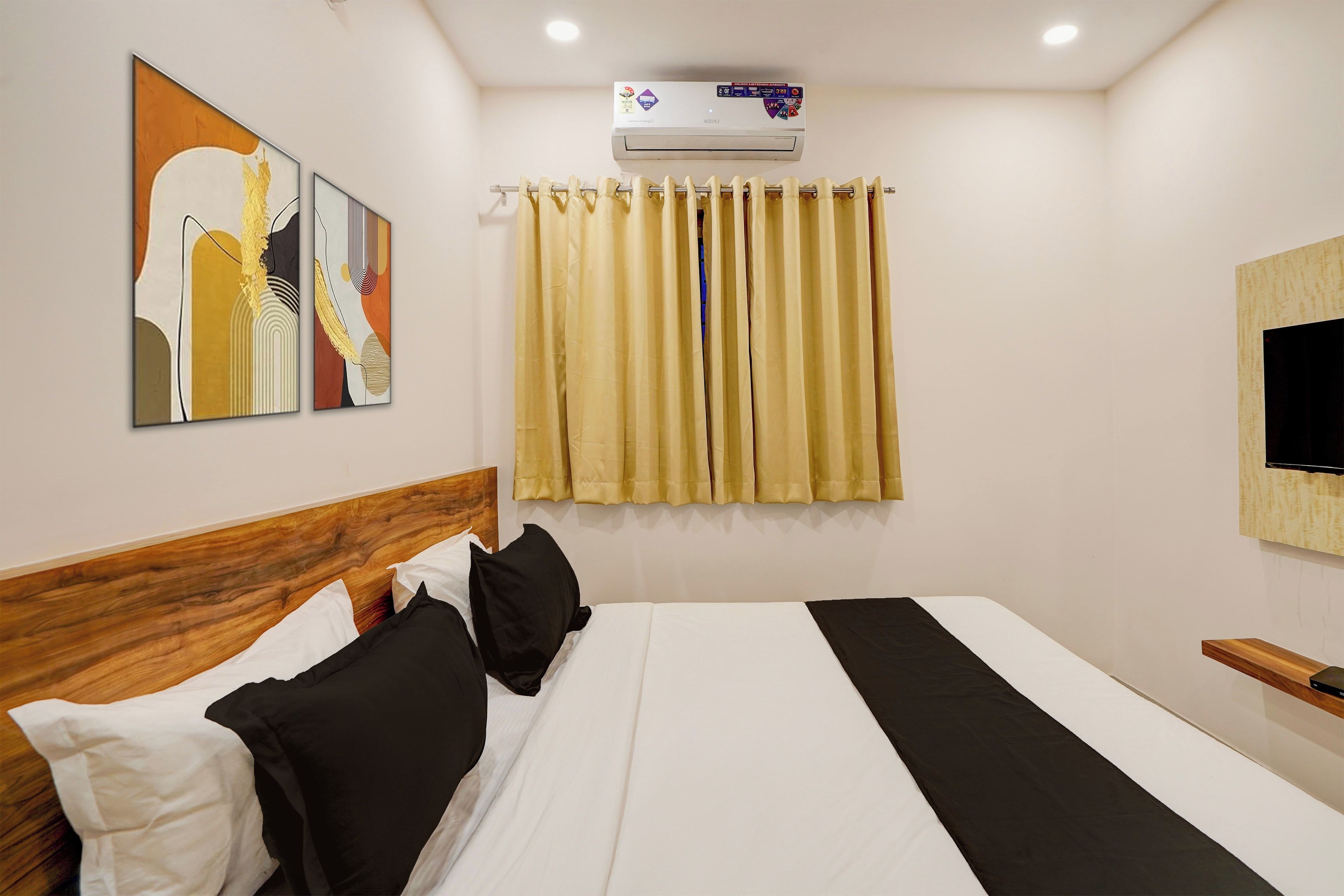Een hotelkamer met een bed, een hoofdeinde, een tv aan de muur en een airconditioning.