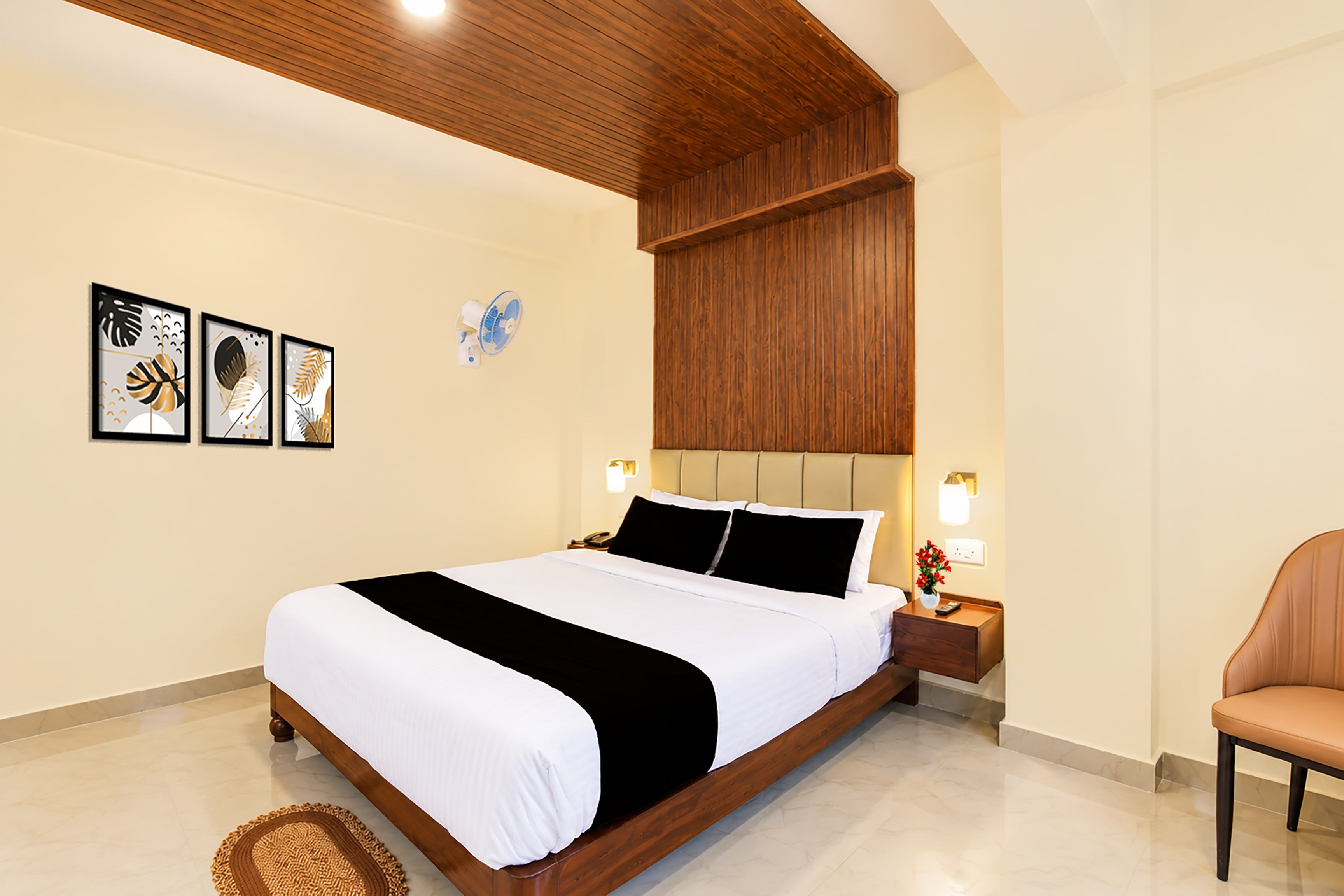 A hotel room with a wooden bed, a bedside table with a lamp, and a chair.