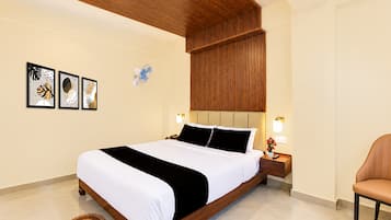 A hotel room with a wooden bed, a bedside table with a lamp, and a chair.