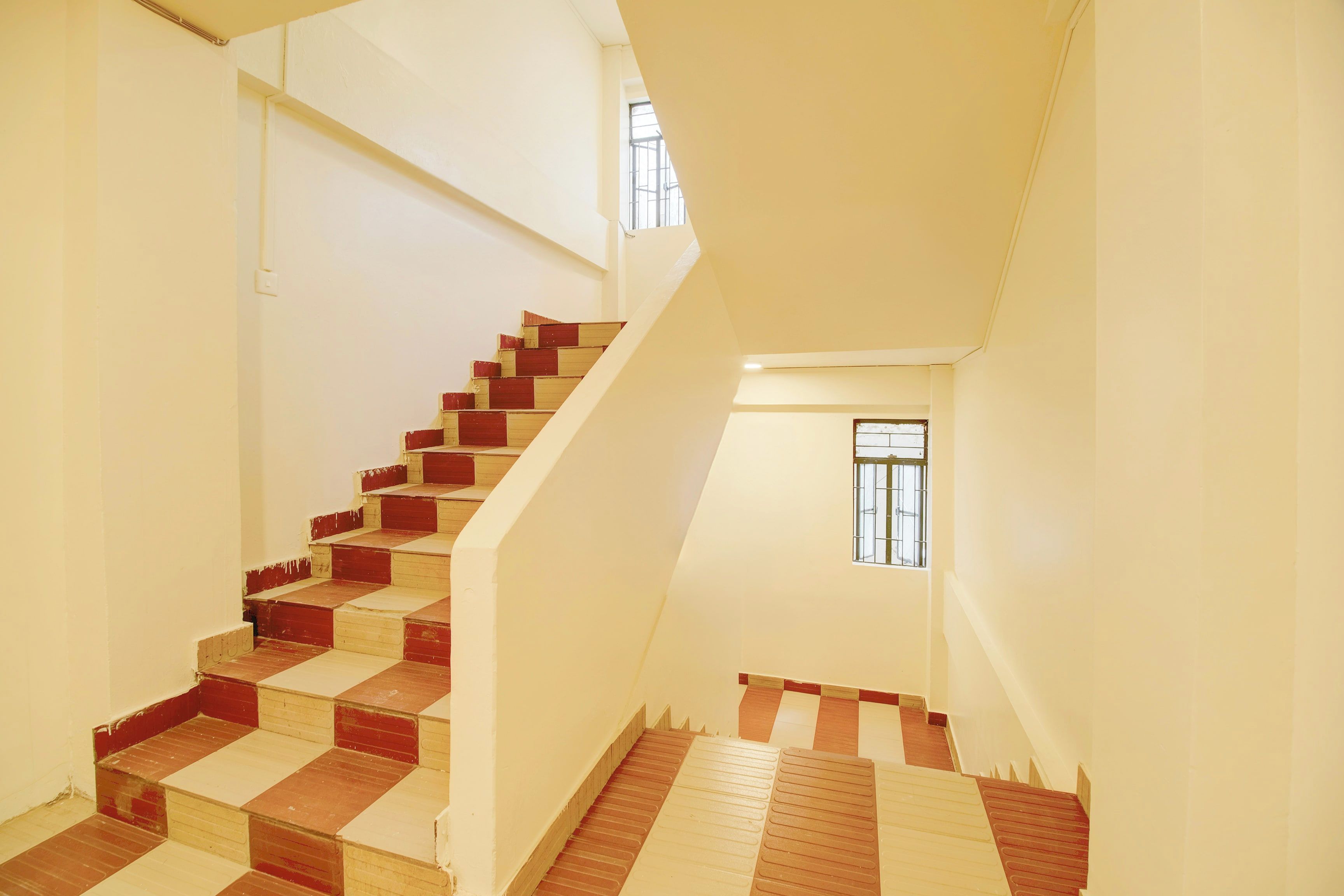 A staircase with alternating red and beige steps leading to a landing.