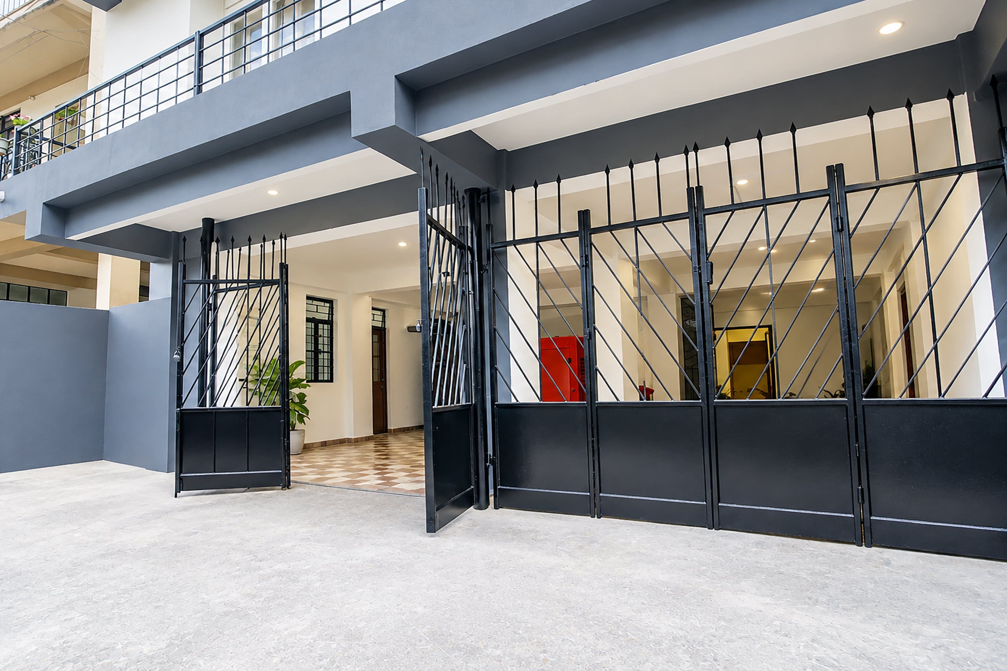 En modern entré till en byggnad med en metallgrind, ett rutmönstrat golv och en balkong.