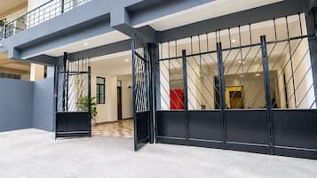 En modern entré till en byggnad med en metallgrind, ett rutmönstrat golv och en balkong.