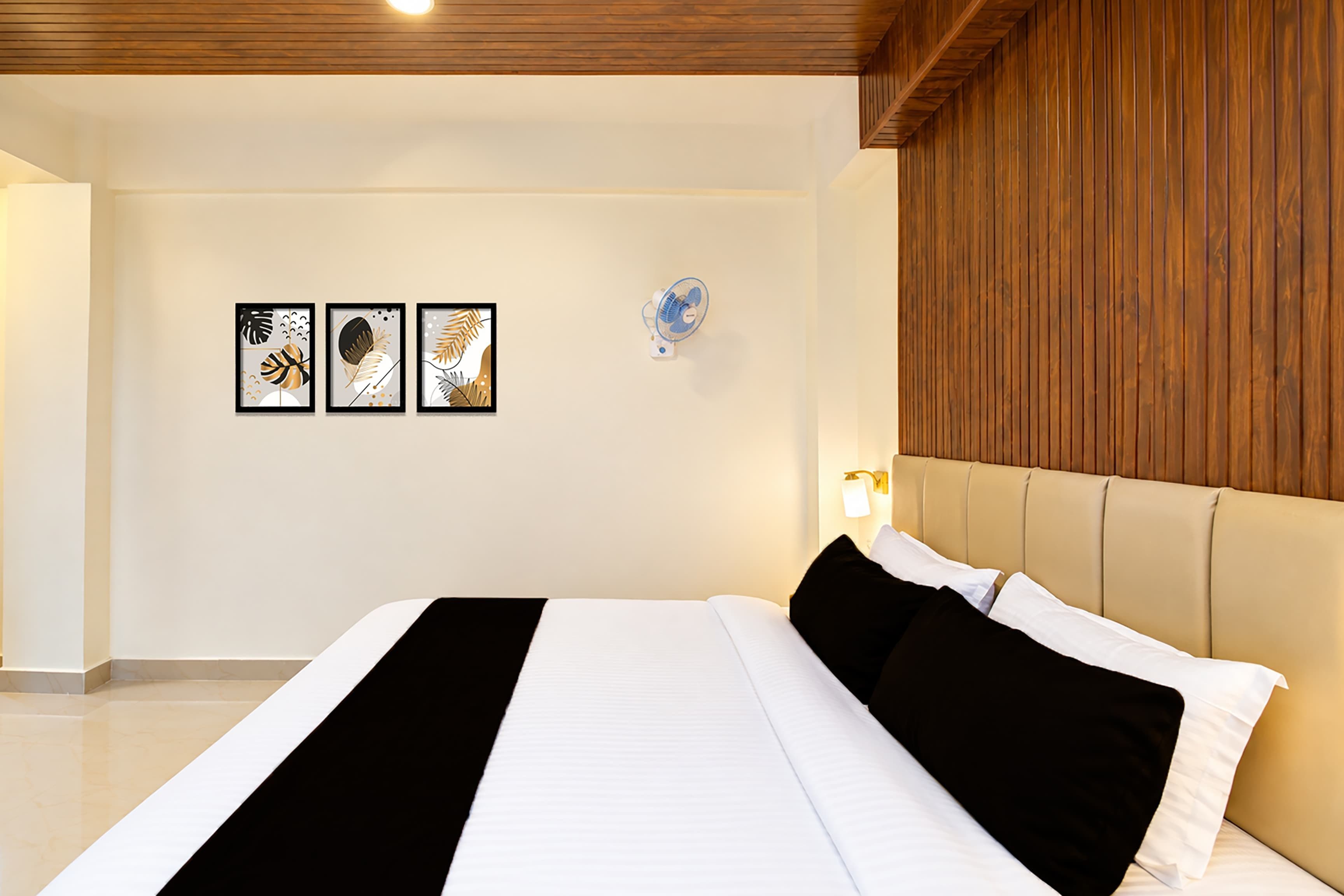 A modern bedroom with a large bed, a wooden headboard, and three framed artworks on the wall.