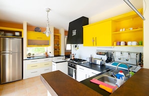 A modern kitchen with a stainless steel refrigerator, a gas stove, and a sink with a faucet. - Villa La Maison P (Kaş)