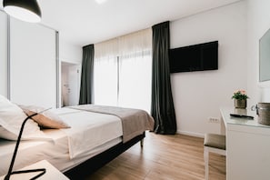 Un dormitorio moderno con cama, mesita de noche y televisión instalada en la pared.