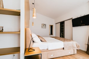 Ein Schlafzimmer mit Bett, Nachttisch, Lampe, Regalen, Kunstwerken und einem Kleiderschrank.