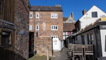 Eine schmale Straße mit traditionellen Backsteingebäuden, ein weißes Gebäude mit der Aufschrift 'The George & Dragon Inn' und ein Holzzaun auf der rechten Seite.
