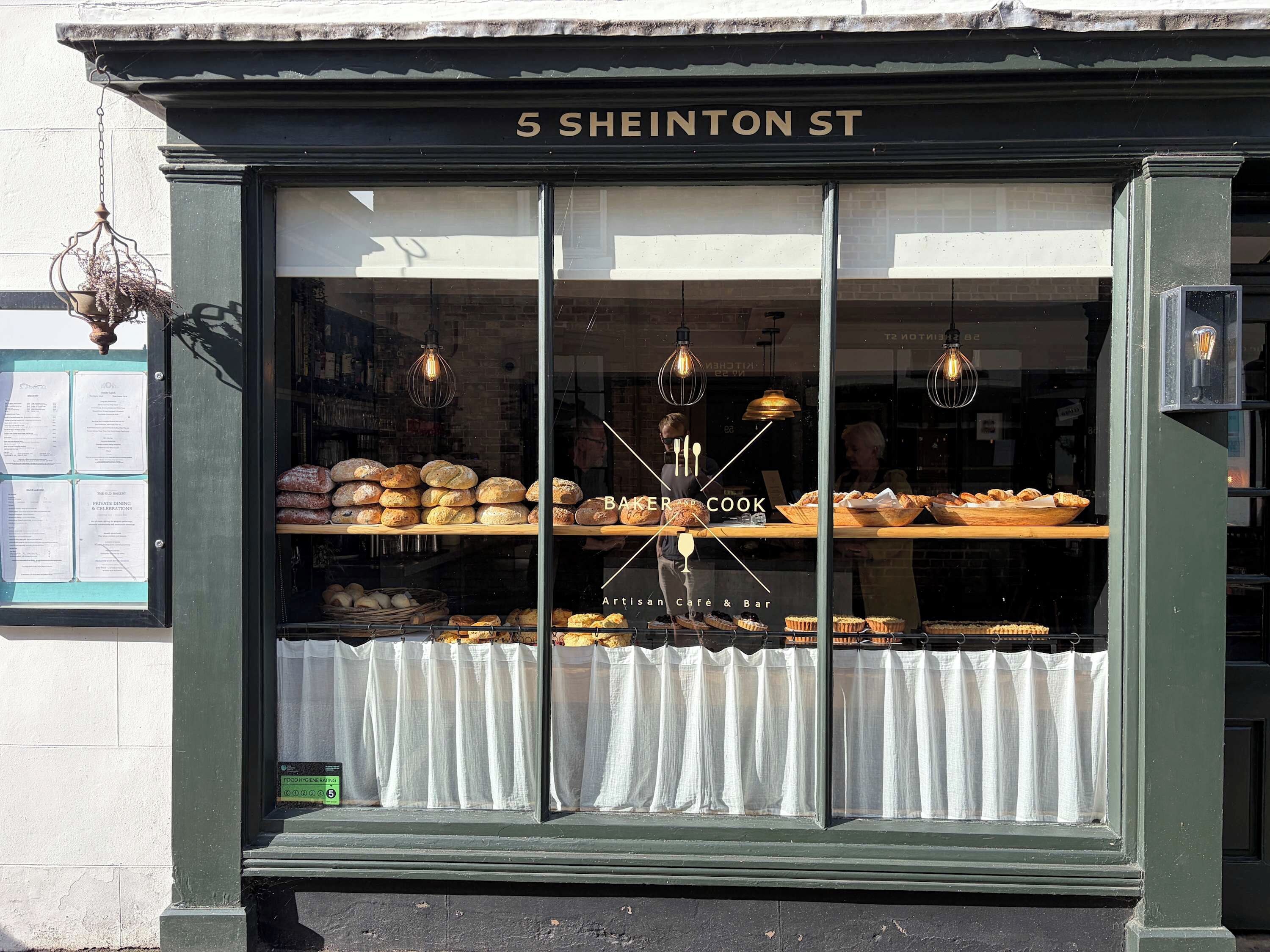 A bakery with a variety of baked goods displayed in the window.