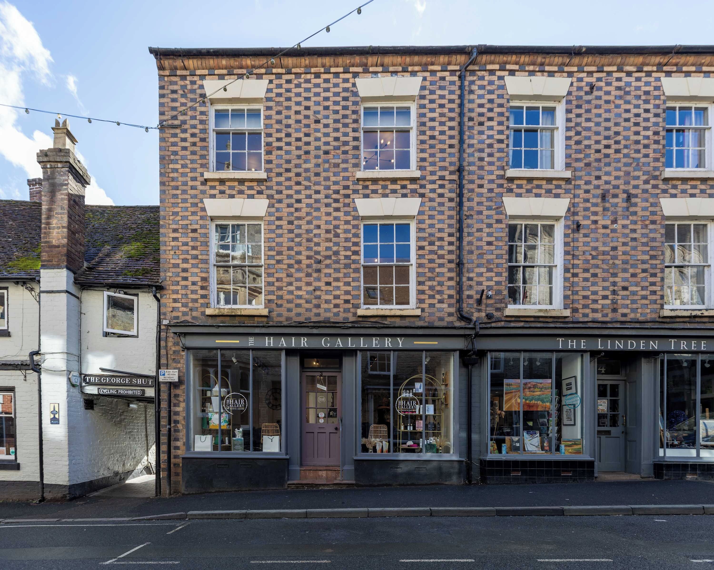 A brick building with two storefronts, one labeled 'The Hair Gallery' and the other 'The Linden Tree'.
