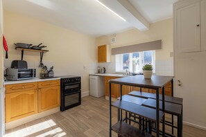 A compact kitchen with wooden cabinets, a built-in oven, a microwave, and a dishwasher.