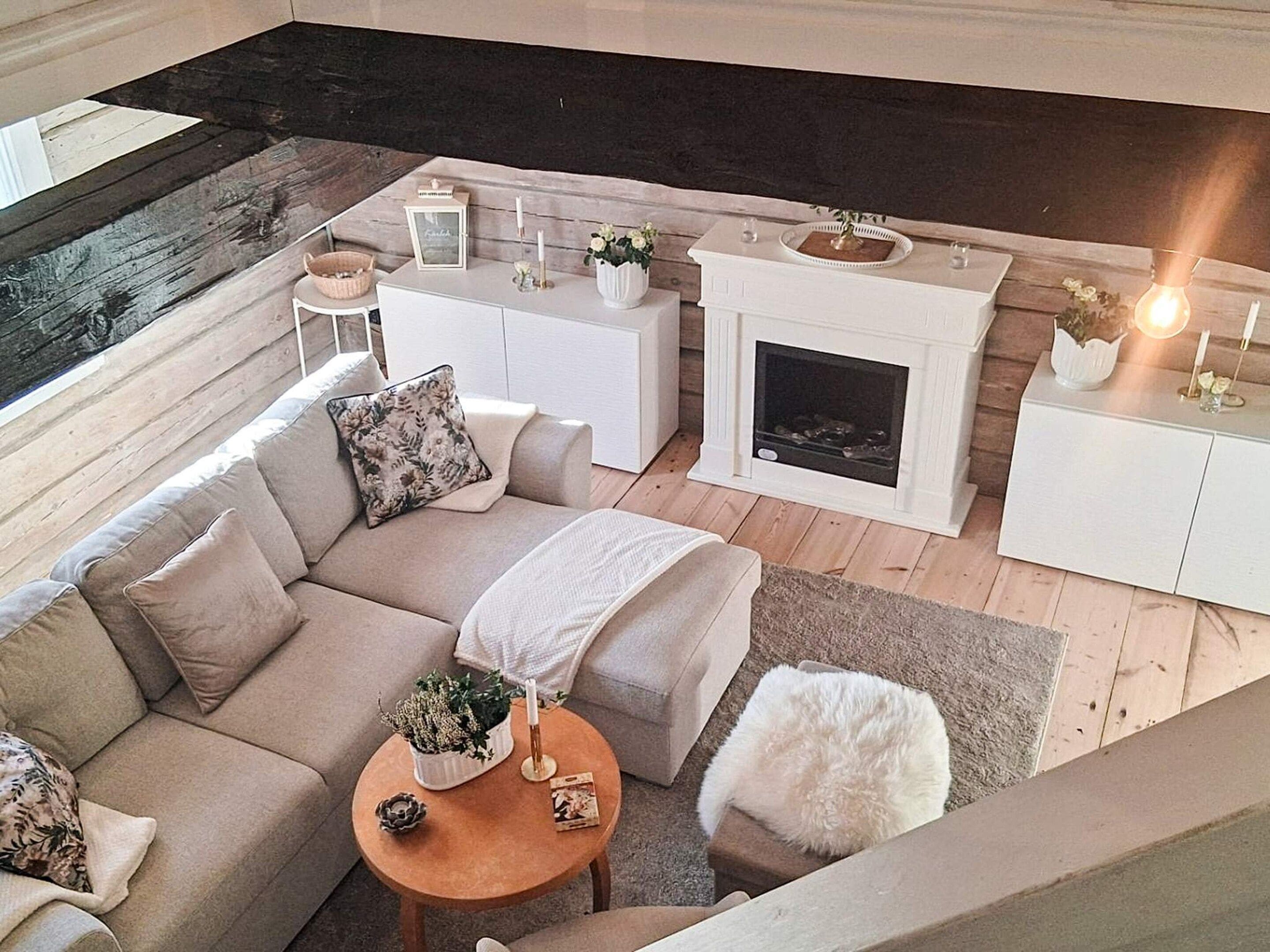 A modern living room with a sofa, coffee table, fireplace, and decorative items.