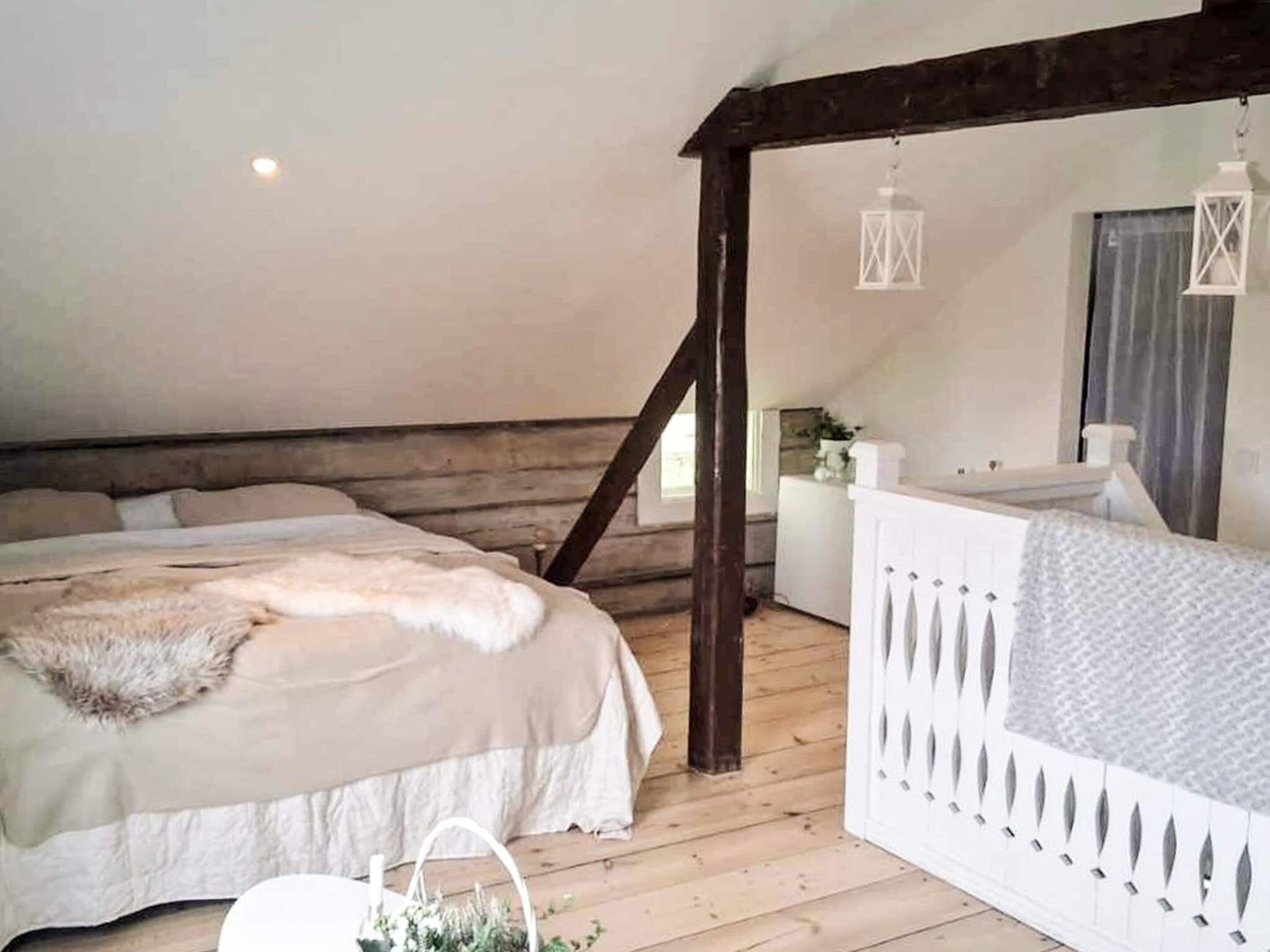 A bedroom with a large bed, wooden beams, a white dresser, and a hanging lantern.