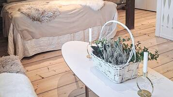 A bedroom with a bed, a white table with a basket, and a dresser.