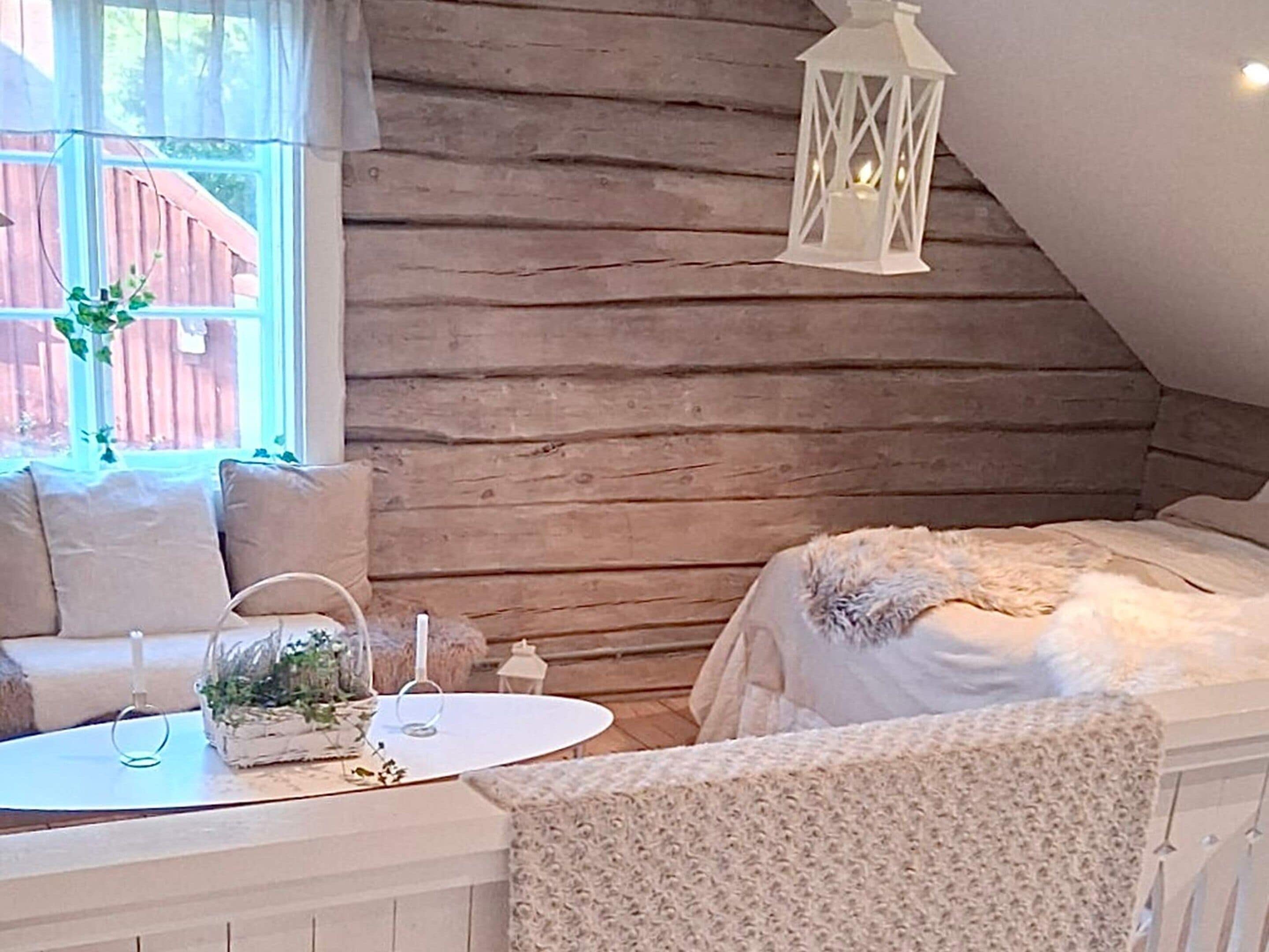 A cozy room with a bed, a small table with a candle, and a chair.