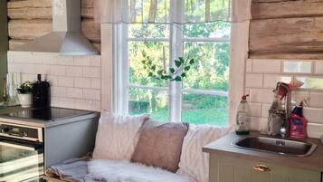 A cozy kitchen with a window, a sink, and a bench with cushions.