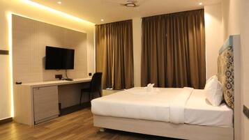 A hotel room with a bed, desk, chair, and a television on the wall.