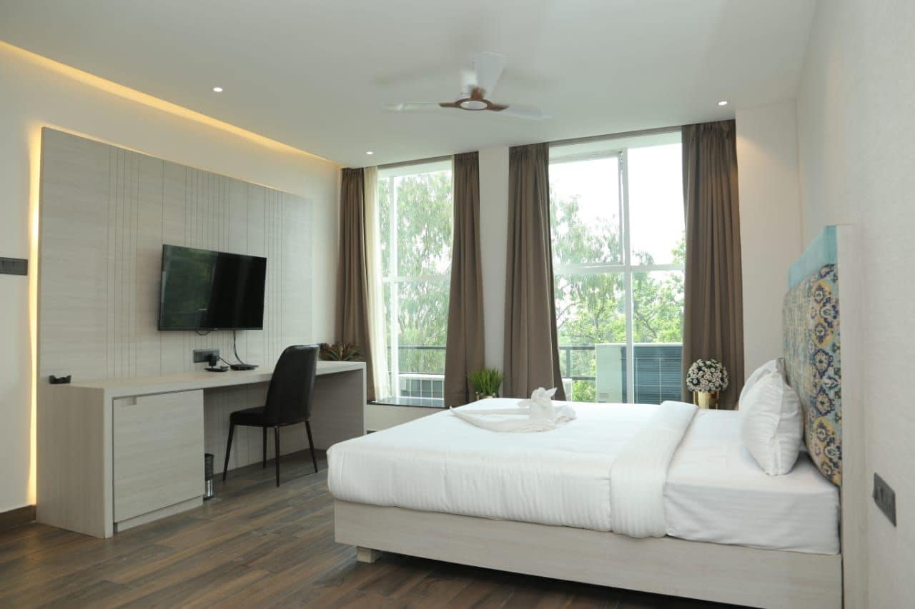 Habitación de hotel moderna con cama, escritorio y televisor.