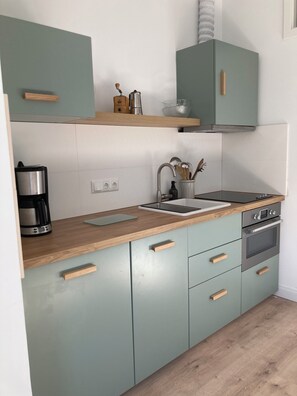 Eine moderne Küche mit Kaffeemaschine, Wasserkocher, Spüle und Herd.