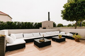 Ein Außenbereich mit Sitzgelegenheiten, einer Couch, zwei Beistelltischen und einem Blumentopf.