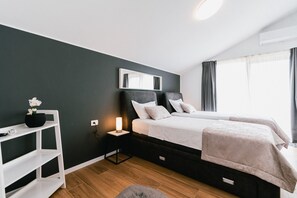 Ein modernes Schlafzimmer mit einem großen Bett, Nachttischen, einem Beistelltisch, einem Spiegel und einem Fenster mit Vorhängen.