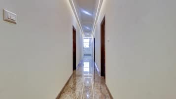 A corridor with a marble floor, white walls, and doors on both sides.