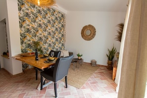 Ein Essbereich mit Holztisch, Stühlen und tropischem Wandpapier.