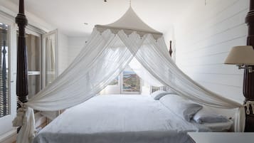 A bedroom with a four-poster bed, a canopy, and a view of the outdoors through a window.