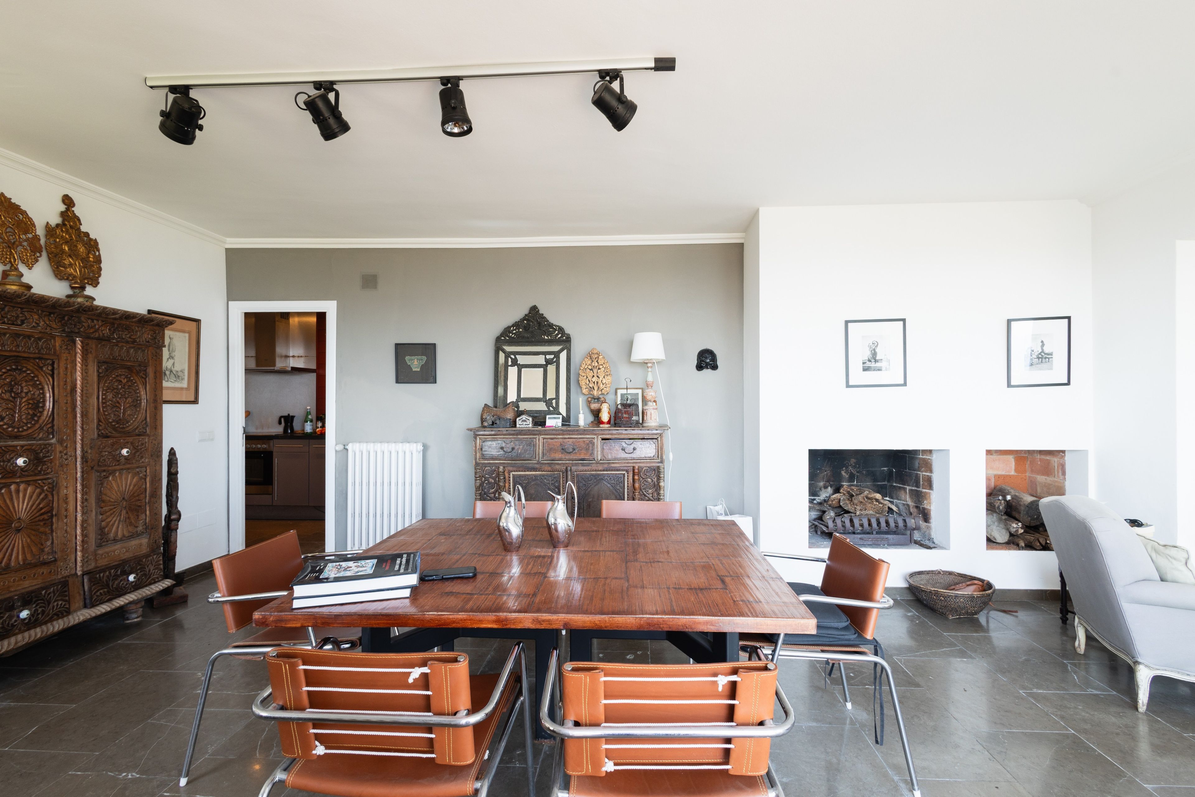 Een eetruimte met een houten tafel, metalen stoelen, een kroonluchter en een open haard.