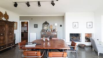 Een eetruimte met een houten tafel, metalen stoelen, een kroonluchter en een open haard.