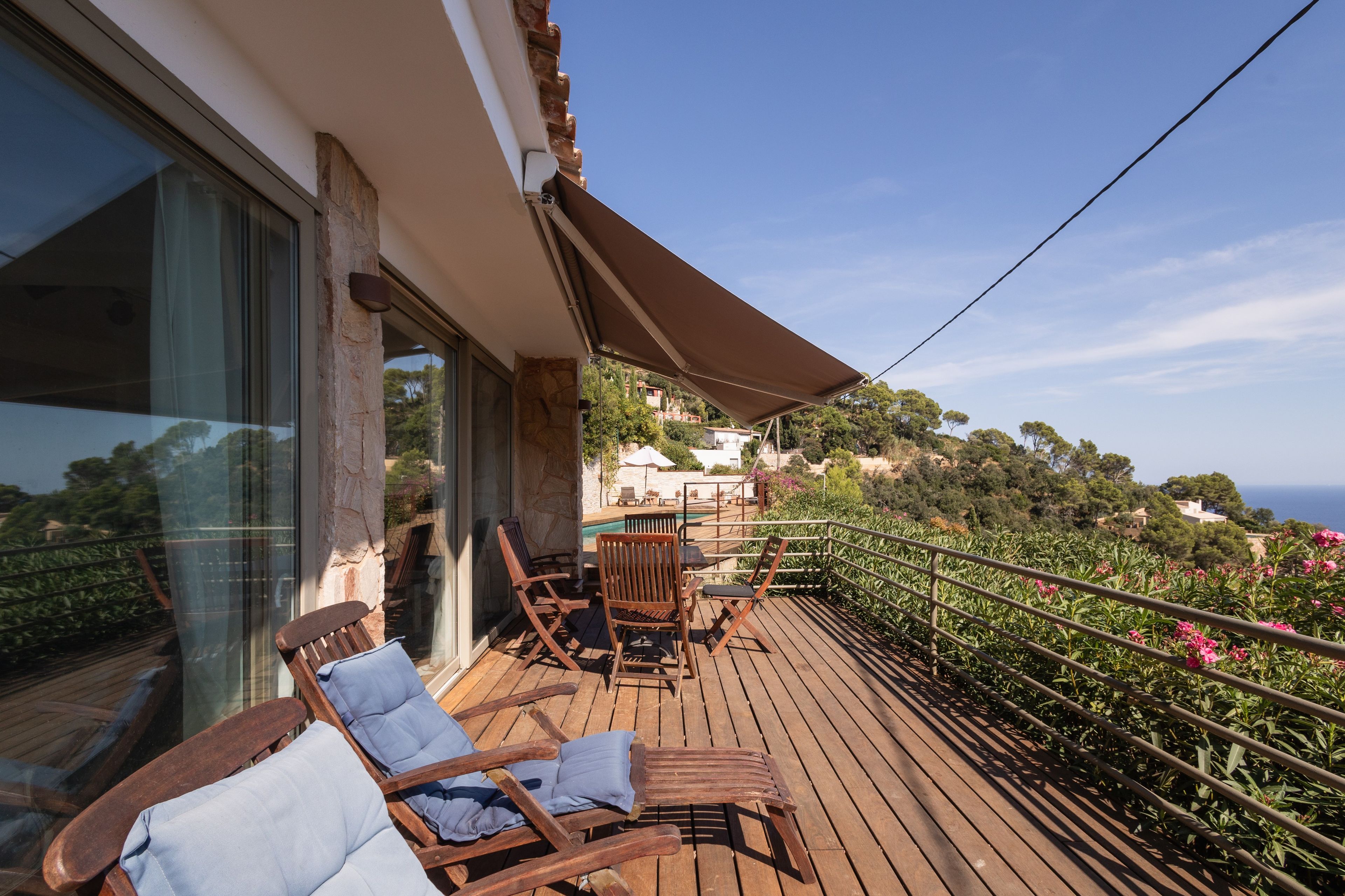 A wooden deck with outdoor furniture, a pergola, and a view of the landscape.