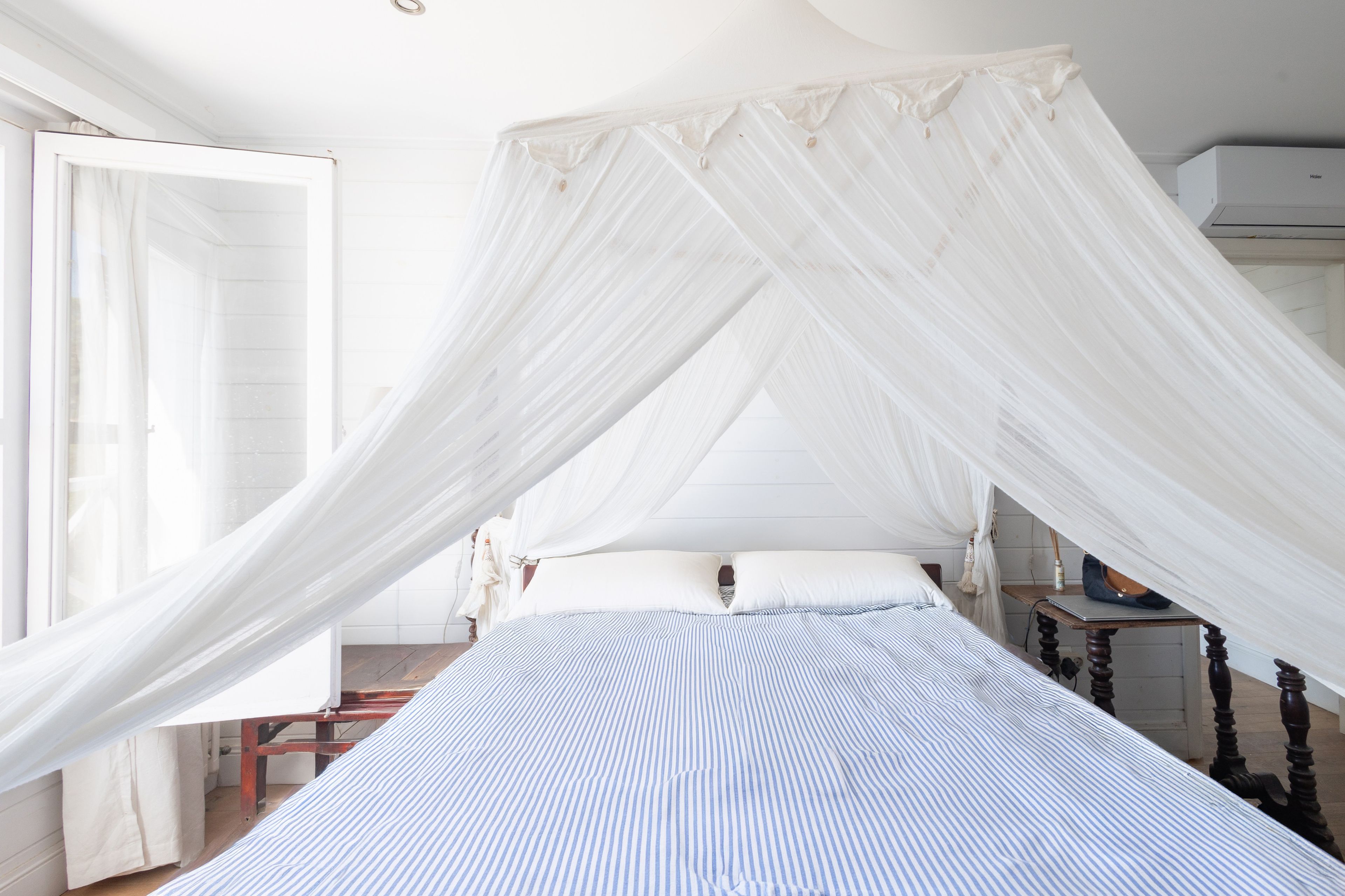 Een bed met hemel, een nachtkastje en een stoel.