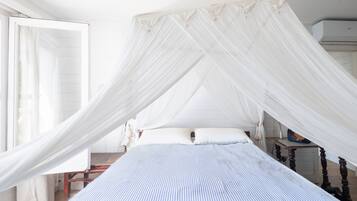 Een bed met hemel, een nachtkastje en een stoel.