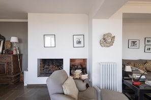 A living room with a fireplace, a sofa, a coffee table, and a bookshelf. - Holiday Home 'Ses Costes' with Sea View, Wi-Fi and Air Conditioning (Begur)