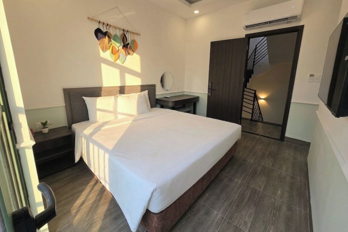 A hotel room with a large bed, a bedside table, a mirror, and a staircase leading to an upper level.